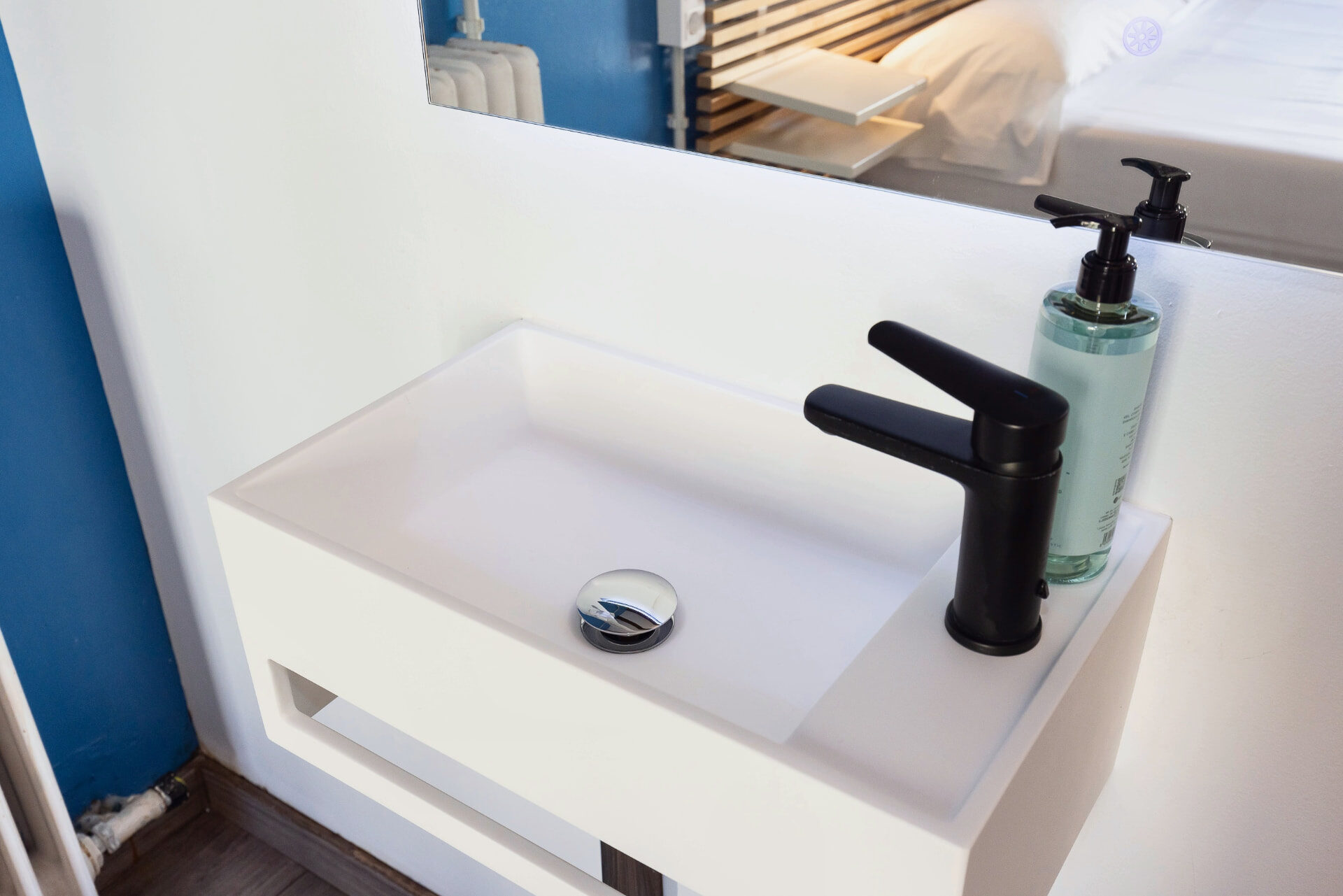 Lavabo blanco con grifería negra y espejo iluminado.