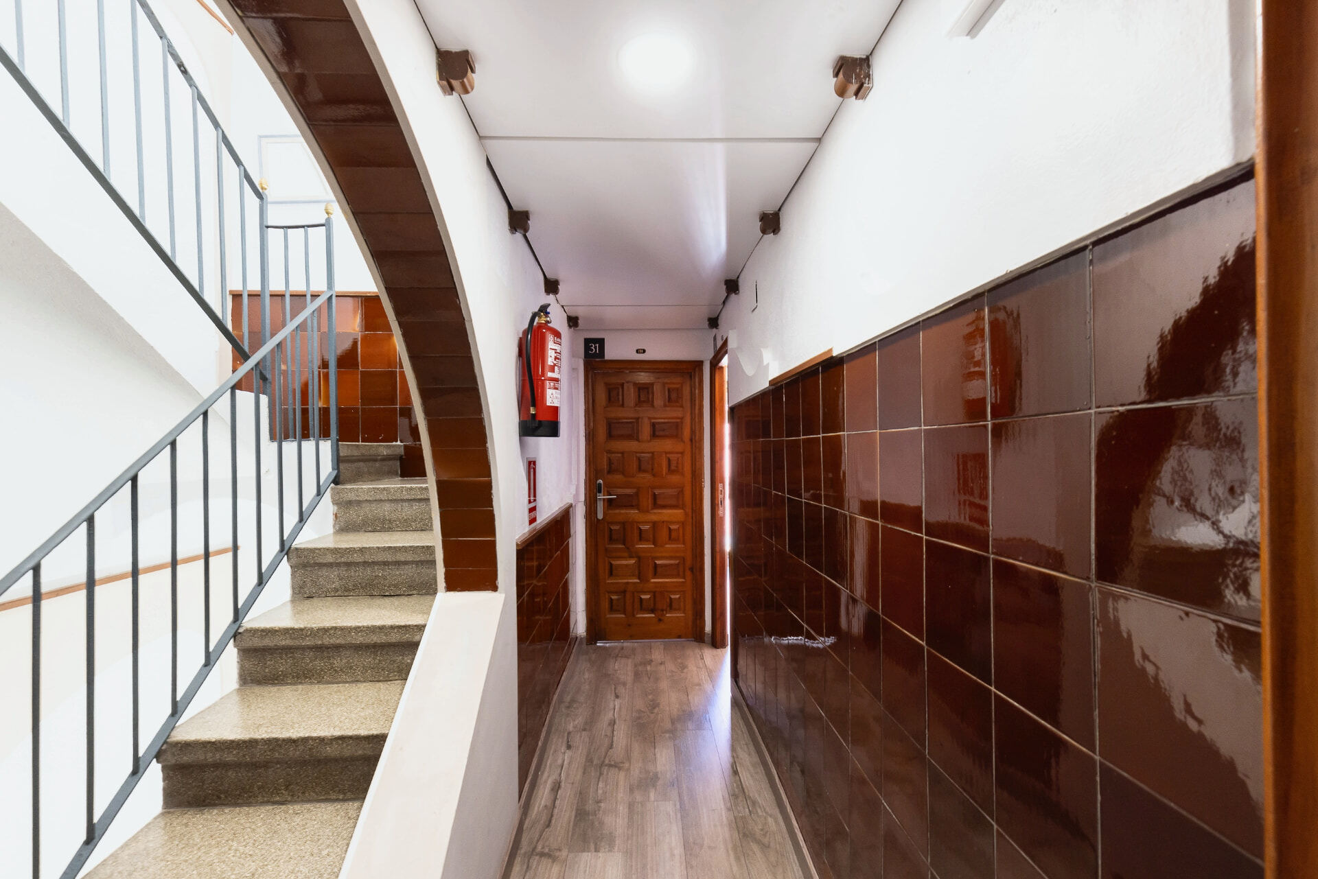 Escalera de terrazo con barandilla negra del hostal.