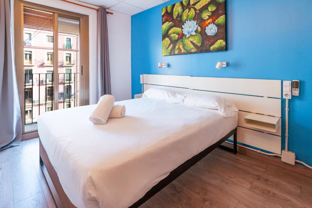 Habitación doble con balcón a la calle, pared azul y cuadro de nenúfares.