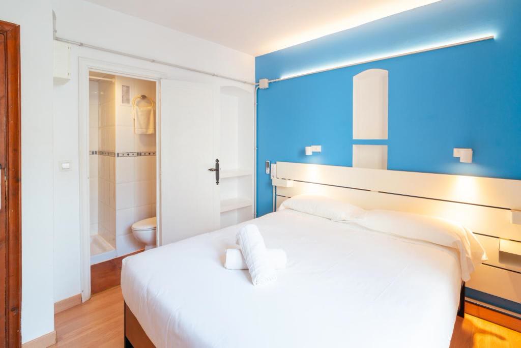 Habitación doble interior con cama de matrimonio, pared azul y baño privado.