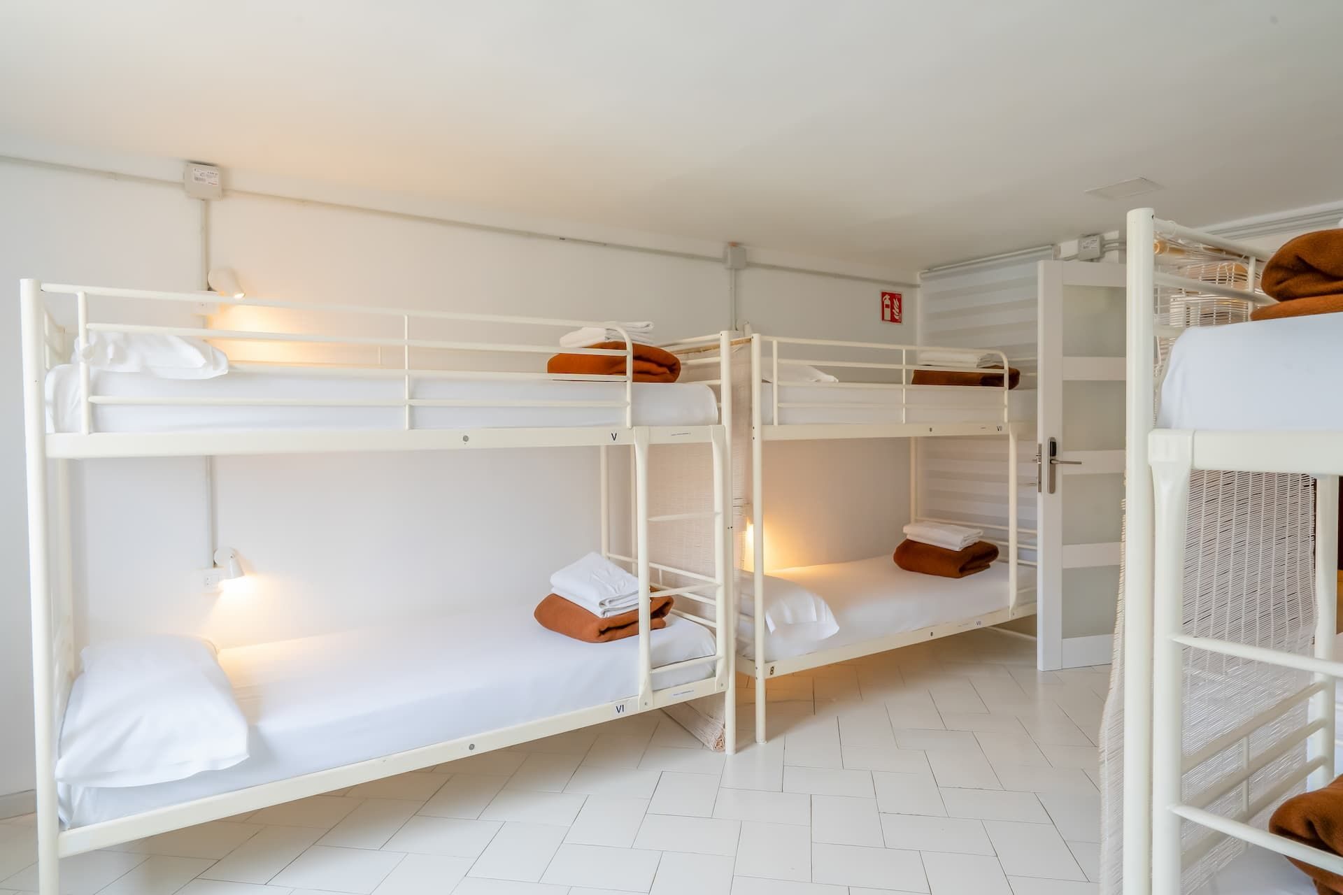 Dormitorio compartido con literas metálicas y luz de lectura en cada cama.