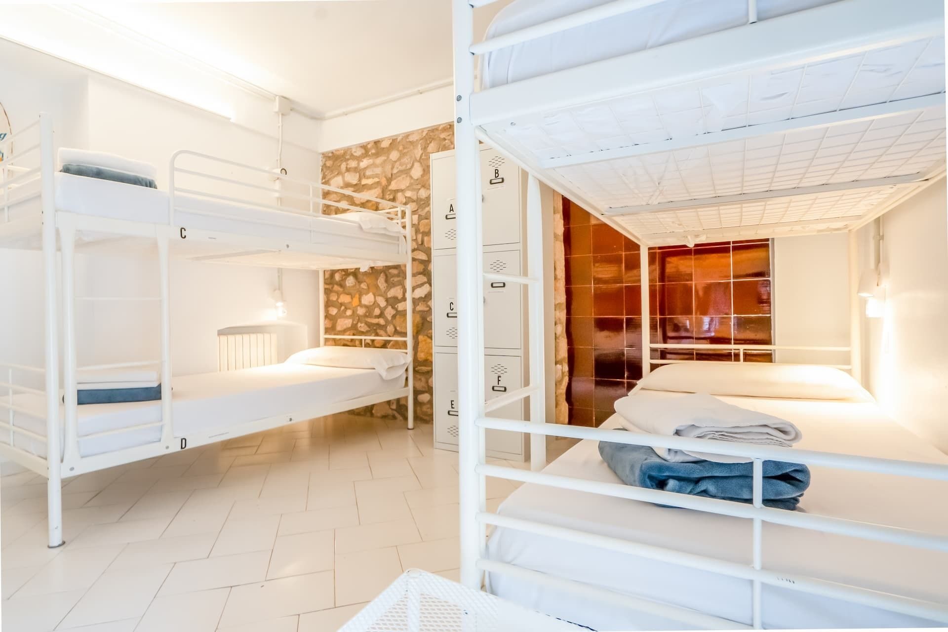 Dormitorio compartido con literas blancas y pared de piedra original.